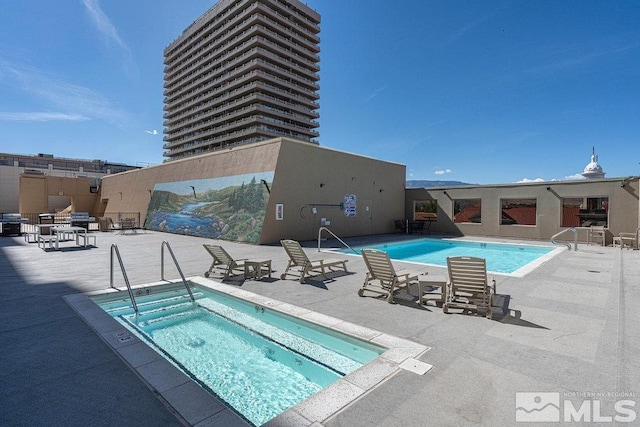 view of swimming pool with a hot tub and a patio