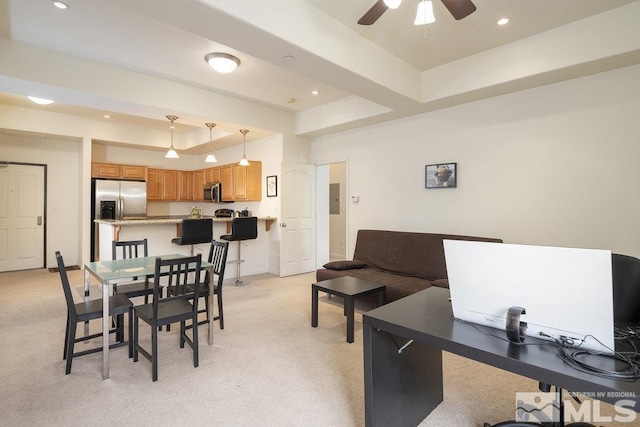 carpeted dining room with a tray ceiling and ceiling fan