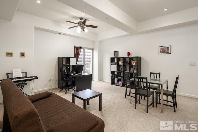 living room featuring ceiling fan, light colored carpet, and a tray ceiling