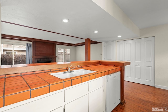 kitchen featuring sink, white cabinetry, tile counters, white dishwasher, and hardwood / wood-style floors