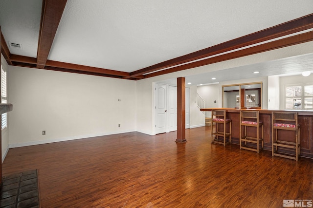 living room featuring beamed ceiling, bar area, and dark hardwood / wood-style flooring