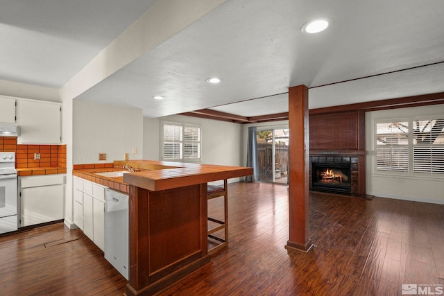 kitchen featuring white cabinetry, dark hardwood / wood-style flooring, kitchen peninsula, plenty of natural light, and white appliances