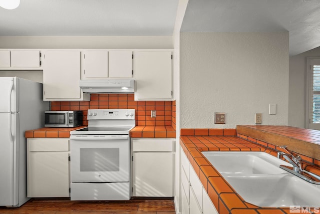 kitchen with white cabinetry, sink, tile counters, and white appliances