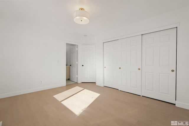 unfurnished bedroom with light wood-type flooring and a closet