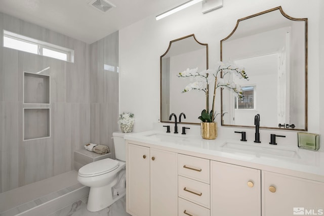 bathroom featuring vanity, tiled shower, and toilet