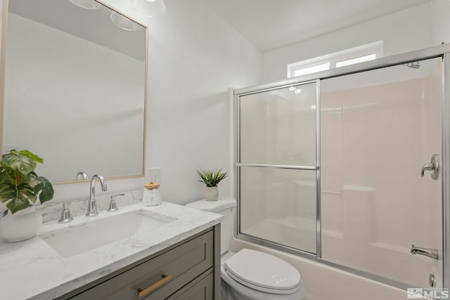 full bathroom featuring shower / bath combination with glass door, vanity, and toilet