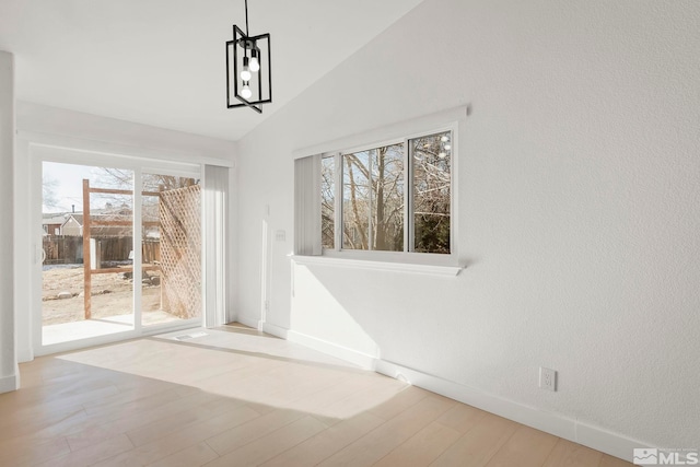 unfurnished dining area with vaulted ceiling and light wood-type flooring