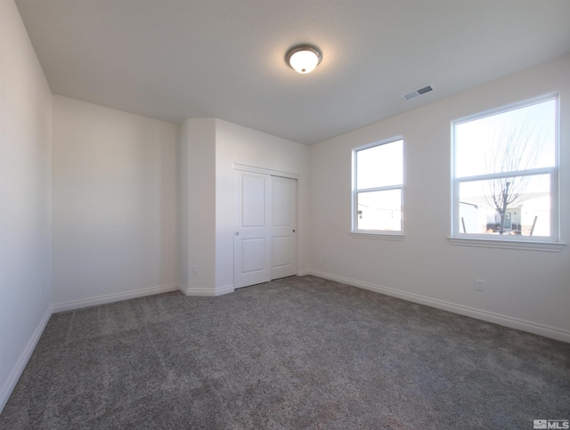 unfurnished bedroom featuring dark carpet and a closet