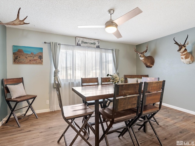 dining room with ceiling fan, light hardwood / wood-style flooring, and a textured ceiling