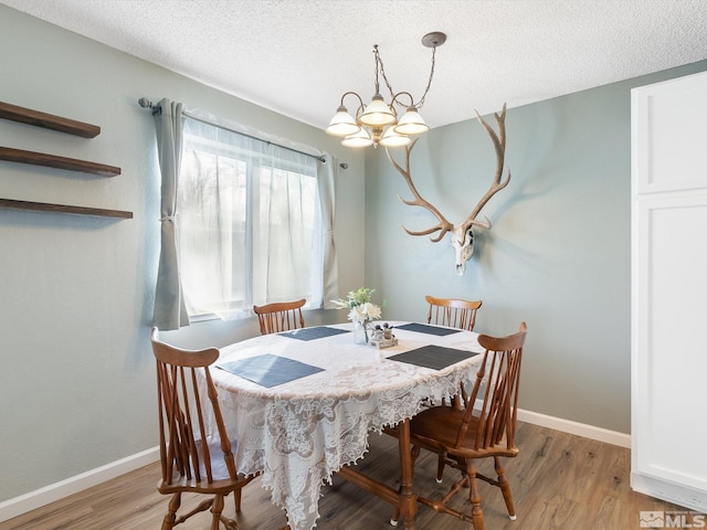 dining area with a notable chandelier, a textured ceiling, and light hardwood / wood-style flooring