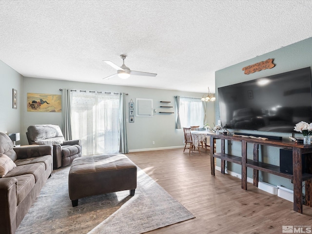 living room featuring wood-type flooring, ceiling fan with notable chandelier, and a textured ceiling