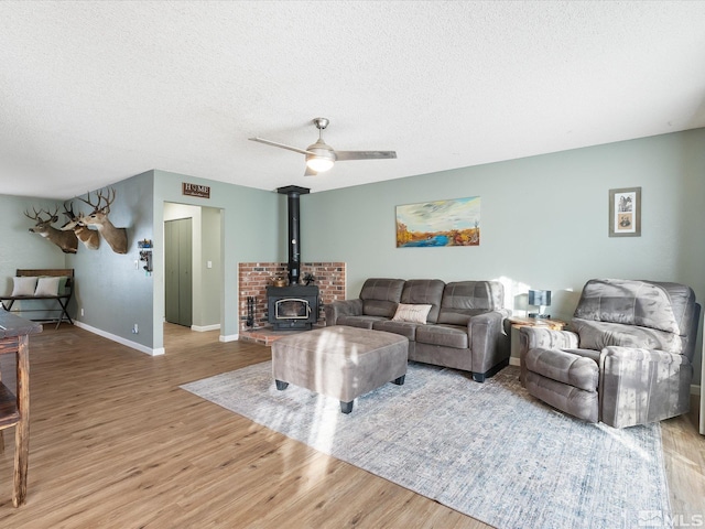 living room with wood-type flooring, a wood stove, and a textured ceiling