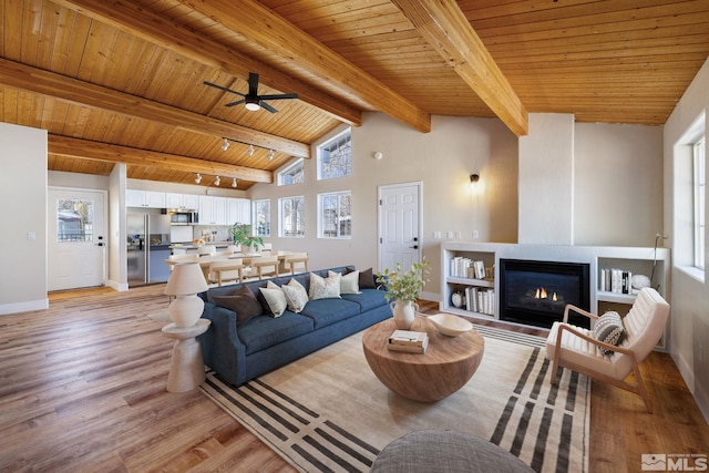 living room featuring a healthy amount of sunlight, wooden ceiling, beam ceiling, and light hardwood / wood-style flooring