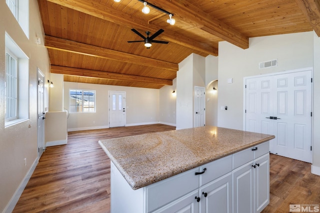 kitchen featuring white cabinetry, vaulted ceiling with beams, a center island, wood ceiling, and light stone counters