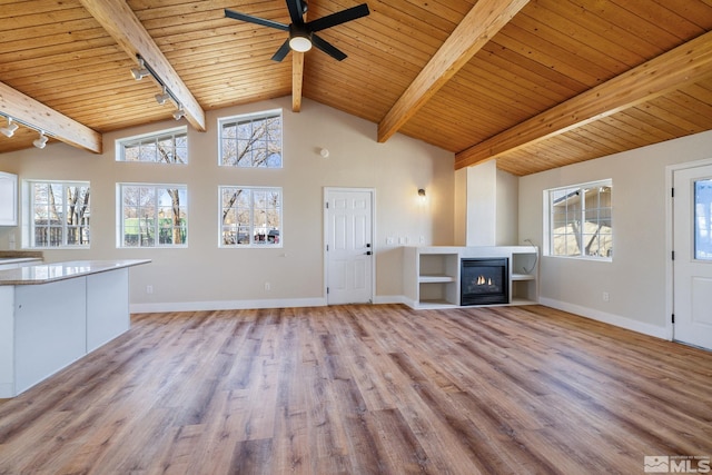 unfurnished living room with wood ceiling, a large fireplace, track lighting, beam ceiling, and light hardwood / wood-style floors