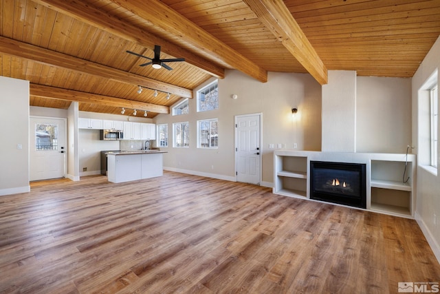 unfurnished living room featuring beam ceiling, light hardwood / wood-style flooring, wooden ceiling, and ceiling fan