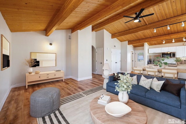 living room featuring light hardwood / wood-style flooring, rail lighting, ceiling fan, wooden ceiling, and beamed ceiling