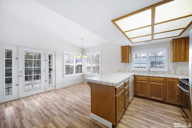 kitchen with lofted ceiling, sink, range with gas cooktop, hanging light fixtures, and kitchen peninsula