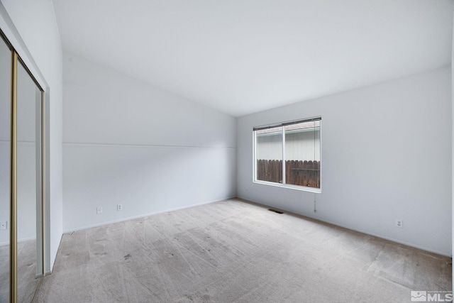 unfurnished bedroom featuring lofted ceiling, light colored carpet, and a closet