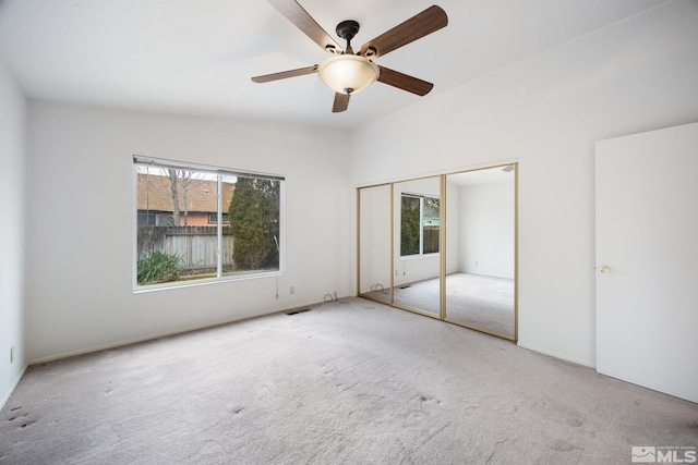 unfurnished bedroom featuring ceiling fan, light colored carpet, lofted ceiling, and a closet