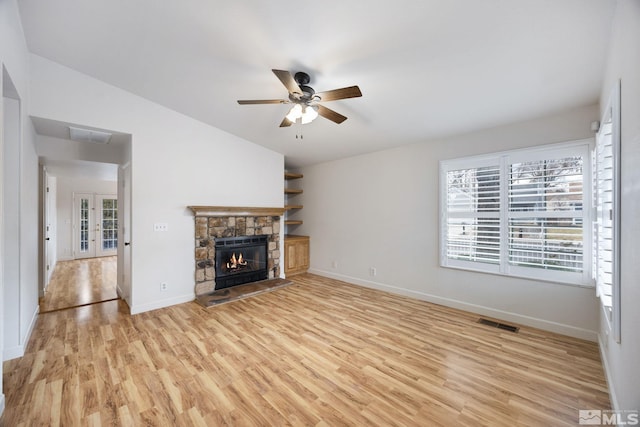 unfurnished living room featuring a stone fireplace, light hardwood / wood-style flooring, ceiling fan, and vaulted ceiling