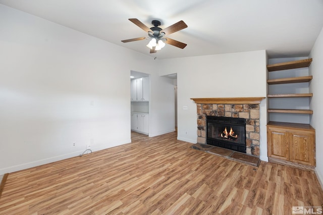 unfurnished living room with ceiling fan, a fireplace, and light hardwood / wood-style floors