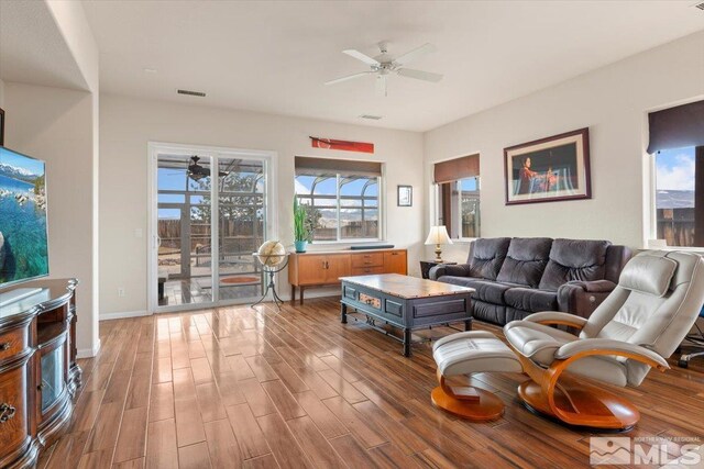 living room featuring wood-type flooring, ceiling fan, and plenty of natural light