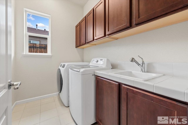 laundry area featuring cabinets, separate washer and dryer, sink, and light tile patterned floors