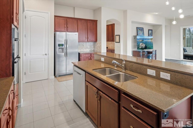 kitchen featuring pendant lighting, sink, appliances with stainless steel finishes, backsplash, and dark stone counters