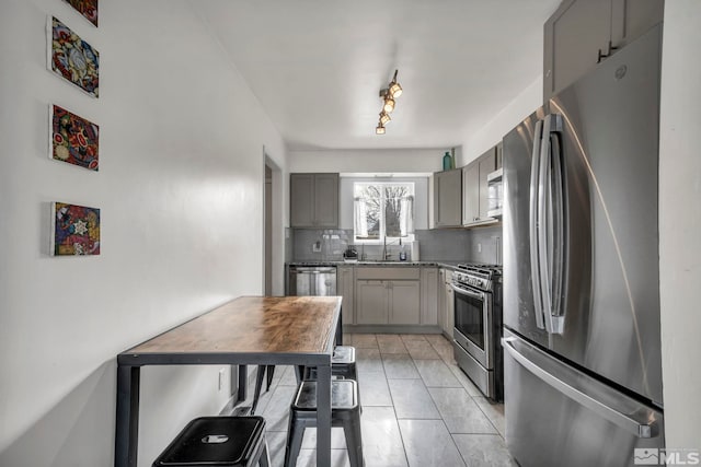 kitchen featuring backsplash, light tile patterned floors, gray cabinets, and appliances with stainless steel finishes