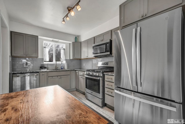 kitchen featuring stainless steel appliances, light tile patterned flooring, gray cabinetry, and backsplash