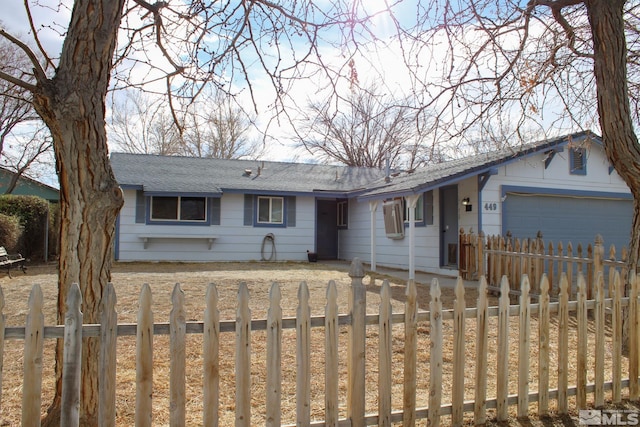 ranch-style house featuring a fenced front yard, roof with shingles, driveway, and a garage