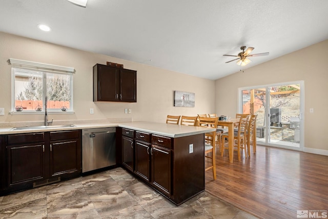 kitchen with a kitchen bar, dark brown cabinetry, sink, stainless steel dishwasher, and kitchen peninsula