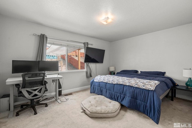 bedroom featuring light carpet and a textured ceiling