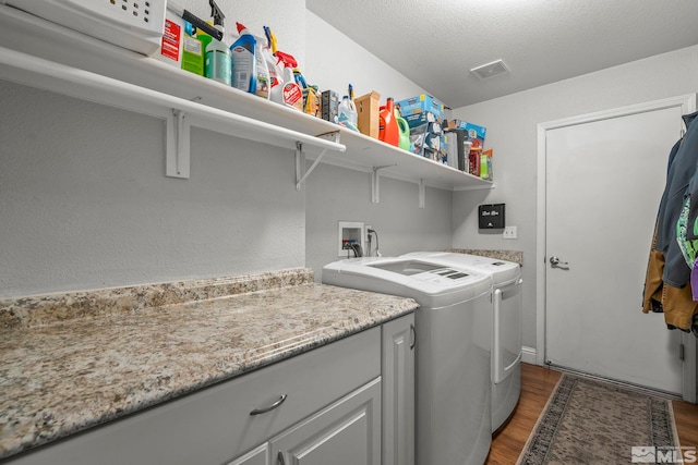 laundry room with washing machine and clothes dryer, dark hardwood / wood-style flooring, and a textured ceiling