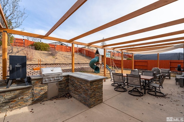 view of patio featuring exterior kitchen, a pergola, grilling area, and a playground