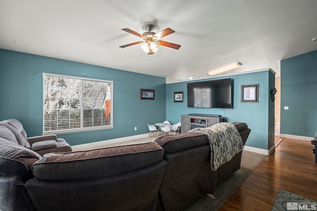 living room with dark hardwood / wood-style flooring, a textured ceiling, and ceiling fan