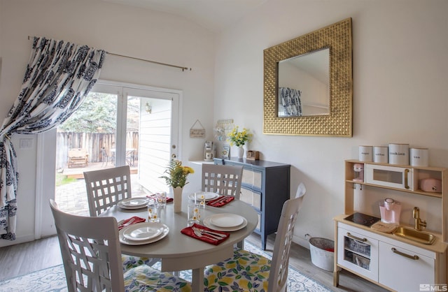 dining area with sink, vaulted ceiling, and light wood-type flooring