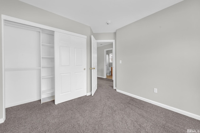 unfurnished bedroom with a closet and dark colored carpet