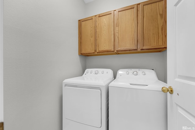 clothes washing area featuring cabinets and separate washer and dryer