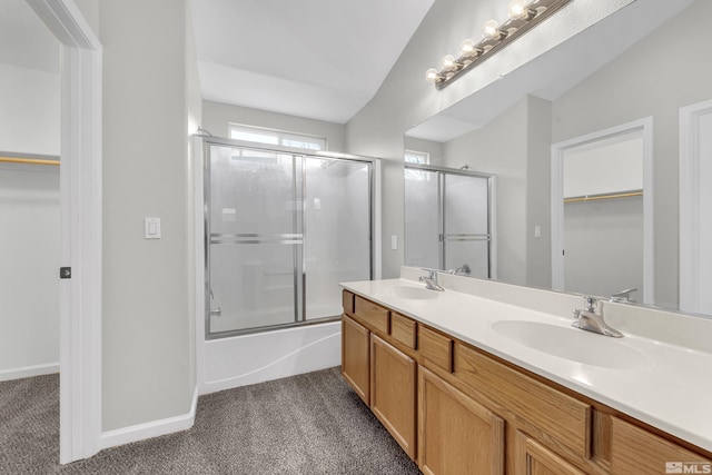 bathroom featuring vanity, vaulted ceiling, and shower / bath combination with glass door