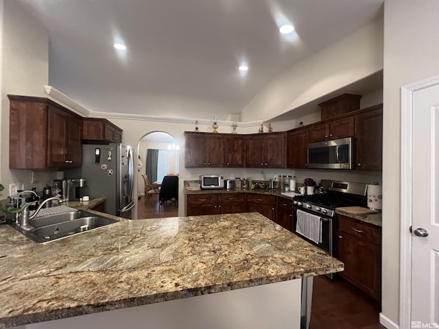 kitchen featuring light stone counters, dark brown cabinetry, stainless steel appliances, and sink