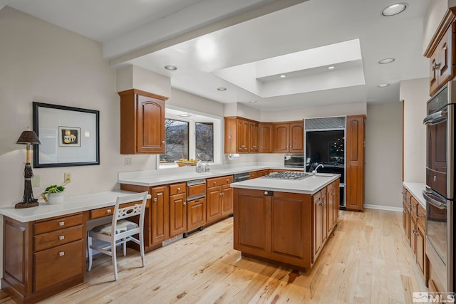 kitchen with a skylight, a raised ceiling, a center island, stainless steel appliances, and light wood-type flooring