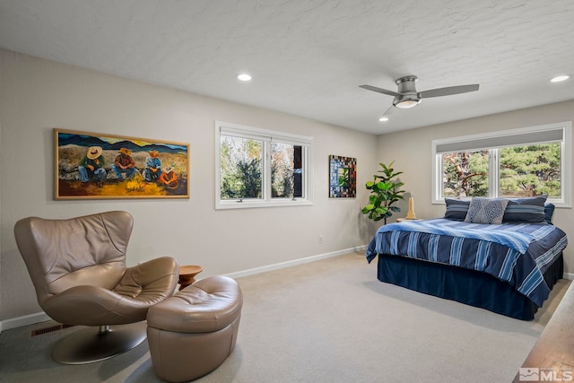 bedroom featuring ceiling fan, light colored carpet, and multiple windows