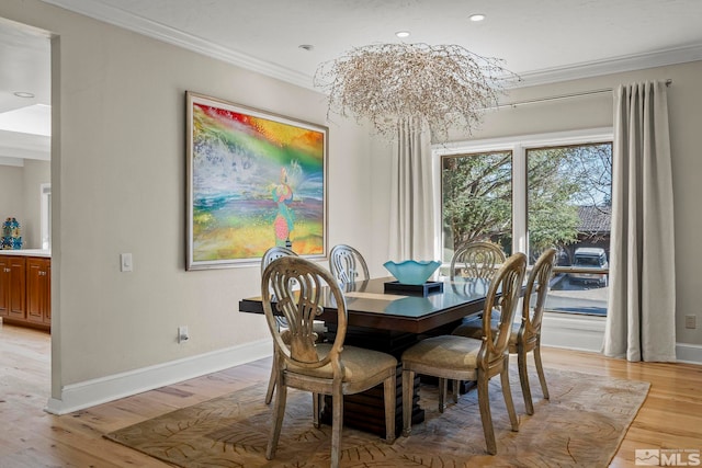 dining area featuring crown molding, an inviting chandelier, and light hardwood / wood-style flooring