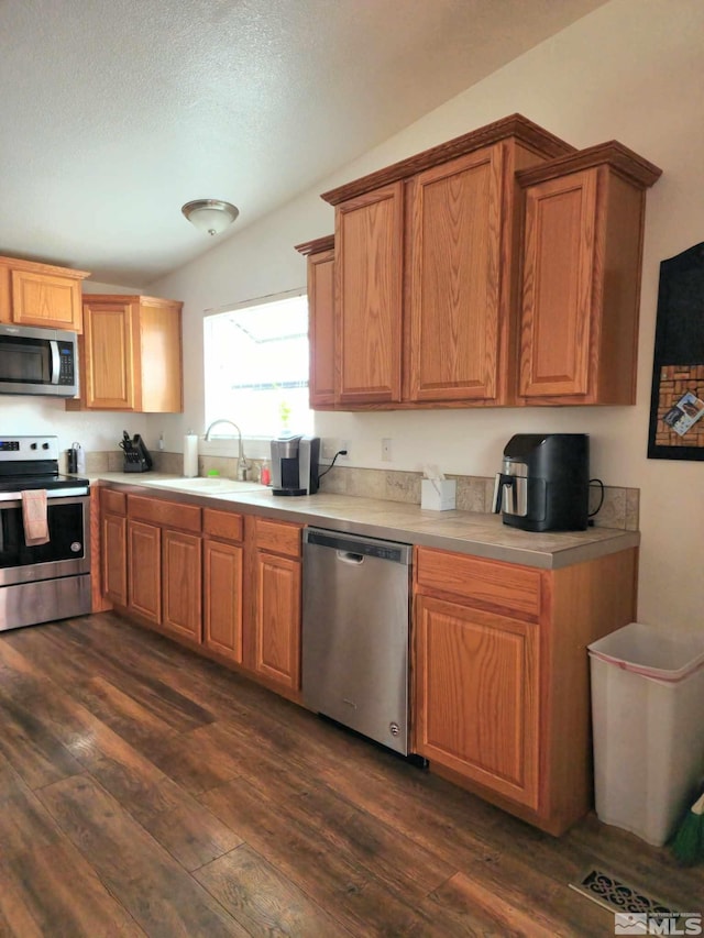 kitchen with lofted ceiling, sink, a textured ceiling, dark hardwood / wood-style flooring, and stainless steel appliances