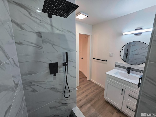 bathroom with a tile shower, vanity, and hardwood / wood-style flooring