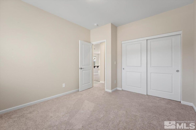 unfurnished bedroom featuring light colored carpet and a closet