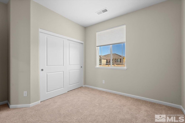 unfurnished bedroom featuring light carpet and a closet