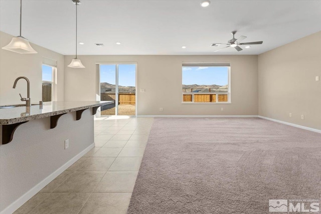 interior space with sink, a breakfast bar area, hanging light fixtures, light tile patterned floors, and light stone countertops